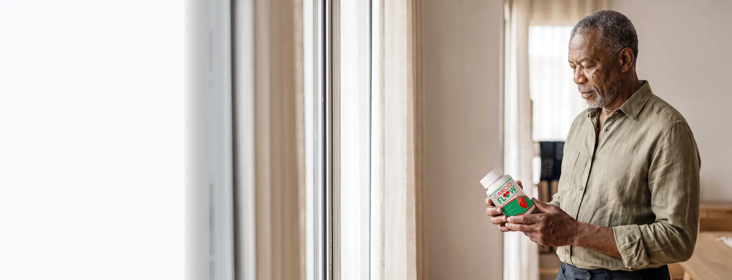 A mature man is holding CardioFlow in a peaceful home setting